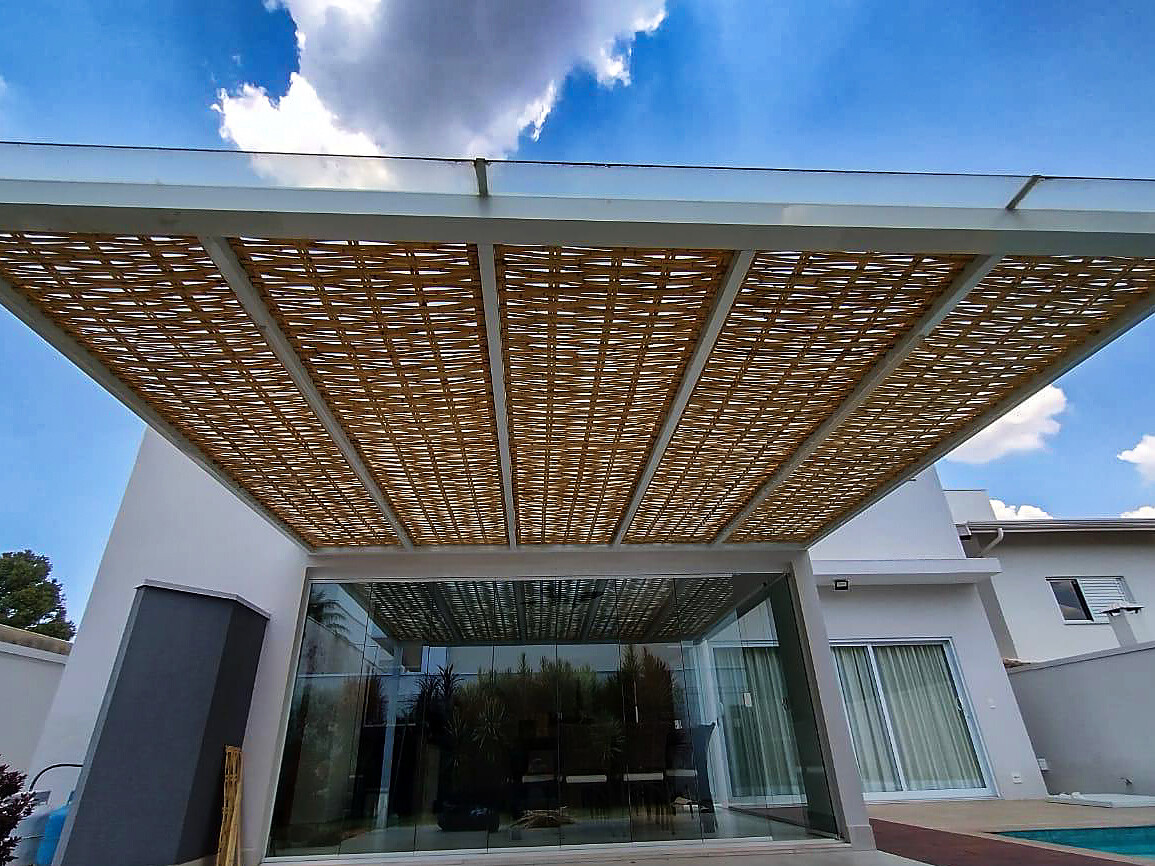 Pergolado contemporâneo com trama de bambu sobre área de piscina